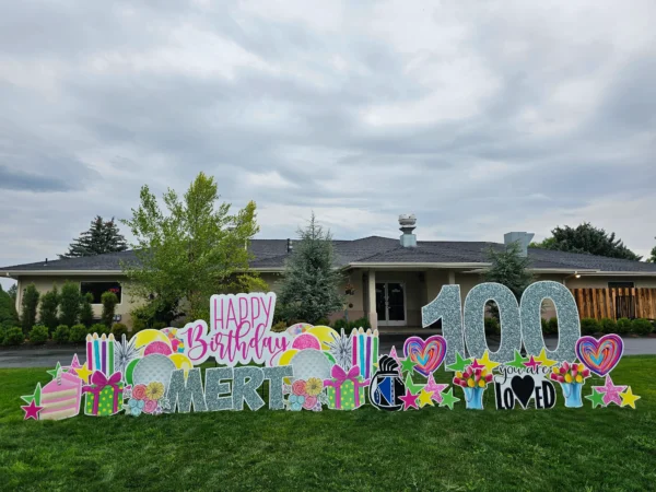 An image of a yard sign with a big number 100, the phrase "Happy Birthday MERT" and other graphics around it.