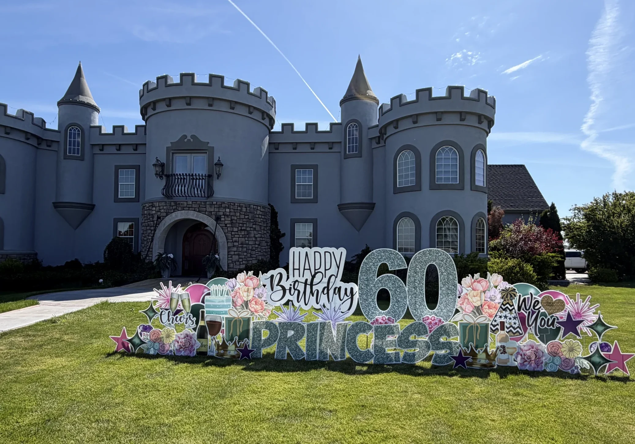 A custom yard sign in front of a castle with a large number 60 with a phrase that says "Happy Birthday Princess"